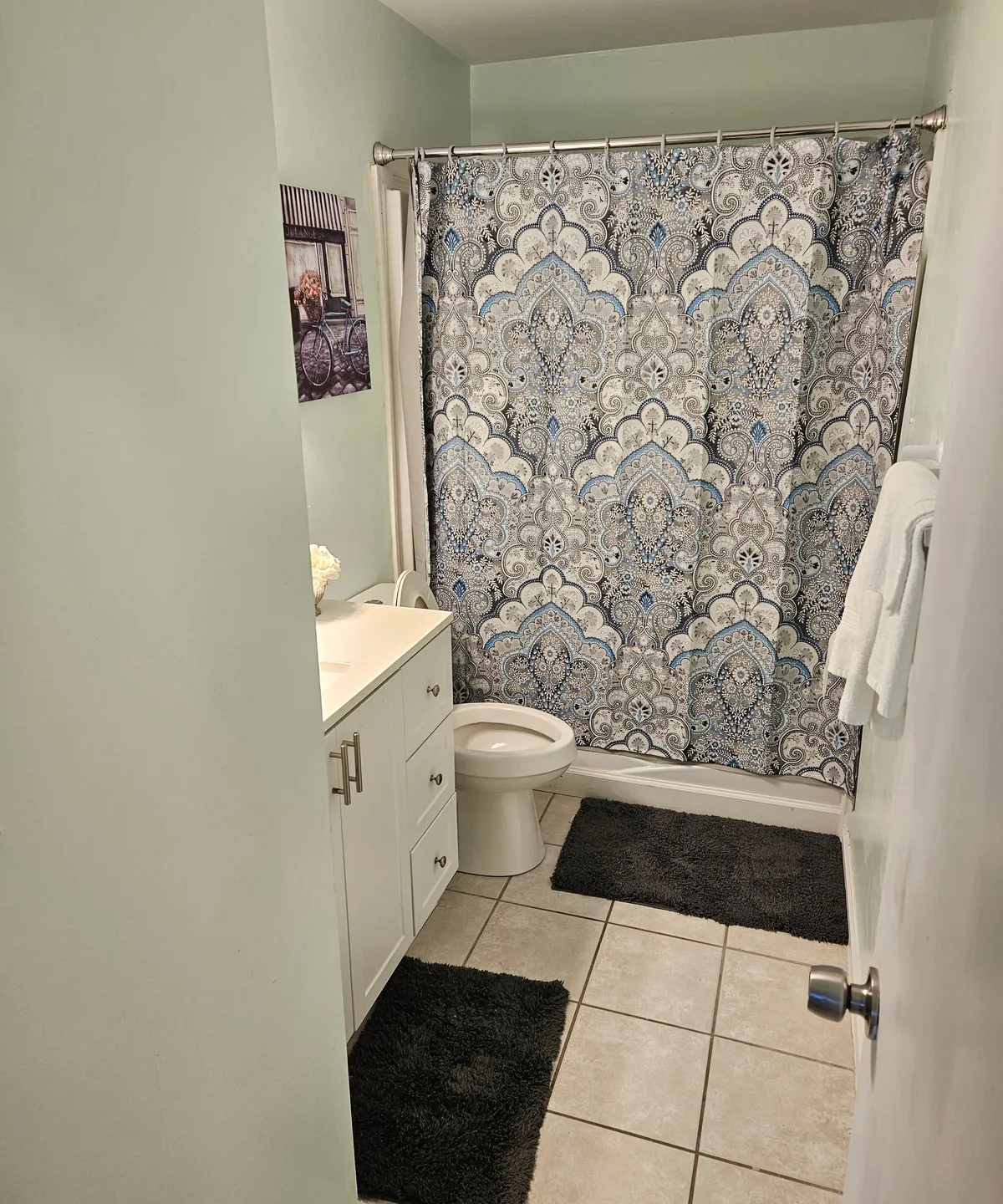 A bright and tranquil bathroom is shown here, featuring a colorful shower curtain, a modern vanity with a sleek sink, and decorative wall art. The space feels fresh and spa-like, inviting guests to refresh and unwind.